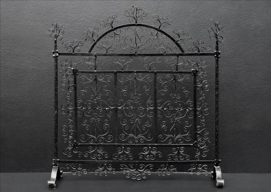 A delicately scrolled wrought iron firescreen