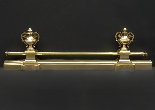 A brass fender with urn finials