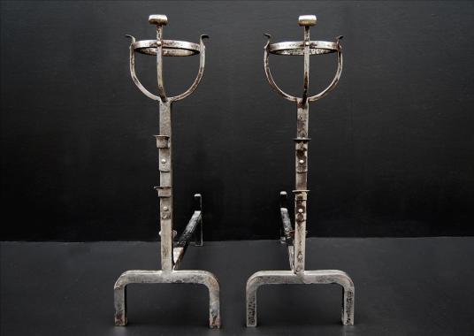 A pair of steel firedogs with mulling tops