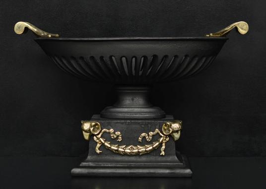 A cast iron bowl grate with brass rams heads