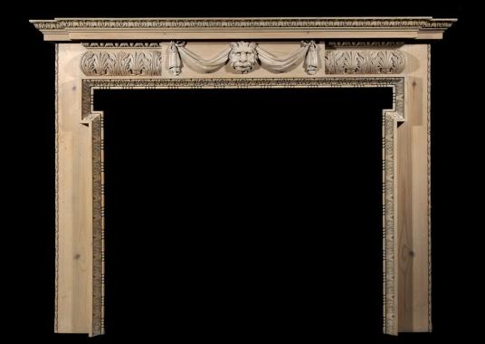 A carved pine fireplace with lion's mask and drapery