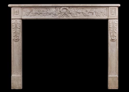 An  ornately carved French limestone fireplace in the Louis XVI style