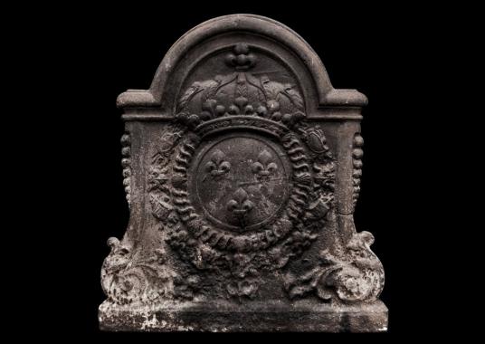 A large, decorative antique cast iron fireback