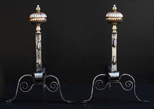 A pair of English polished steel firedogs with brass finial