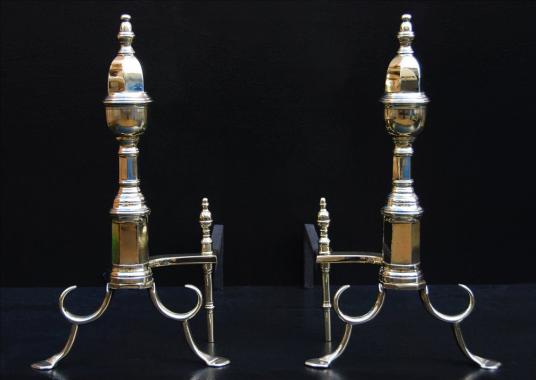 A pair of English brass firedogs with hexagonal shafts