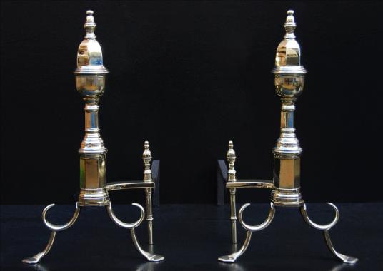 A pair of English brass firedogs with hexagonal shafts