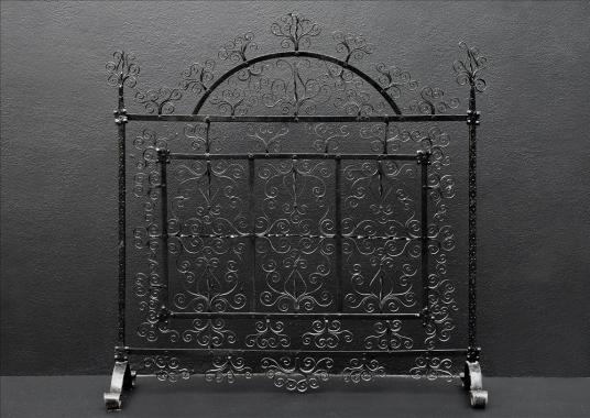 A delicately scrolled wrought iron firescreen