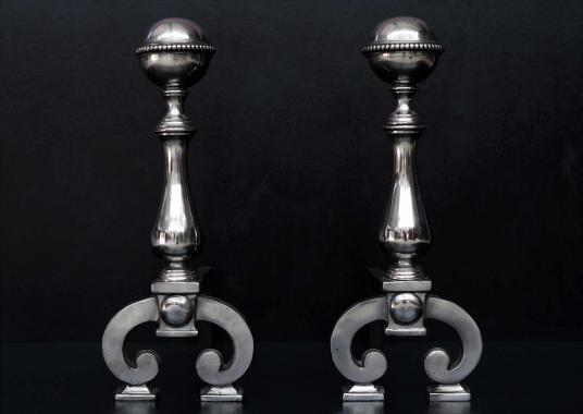 A pair of polished steel firedogs with beading to top