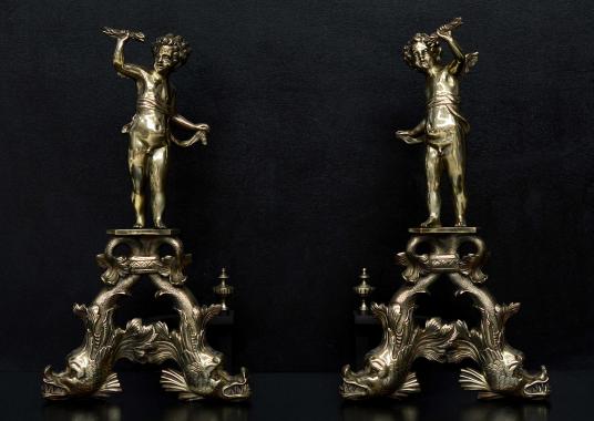 A large pair of brass firedogs with cherubs