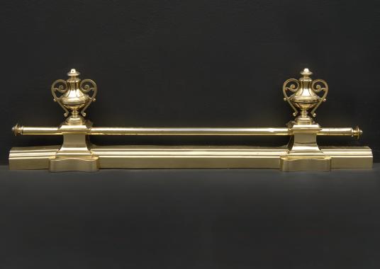 A brass fender with urn finials