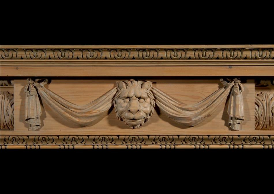 A carved pine fireplace with lion's mask and drapery