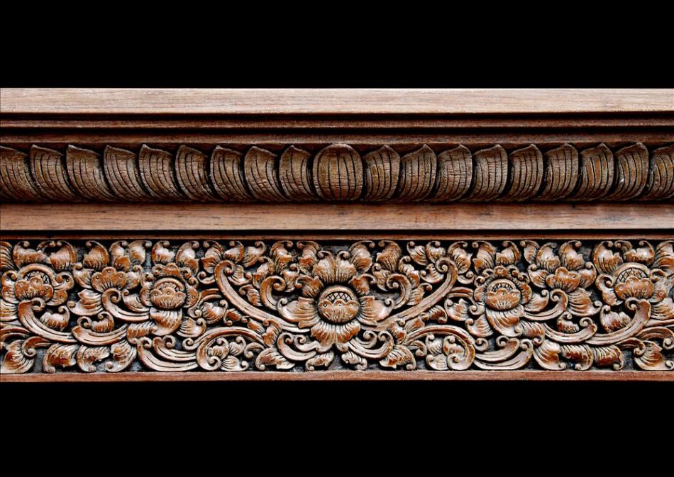 A heavily carved hardwood fireplace with an Oriental influence