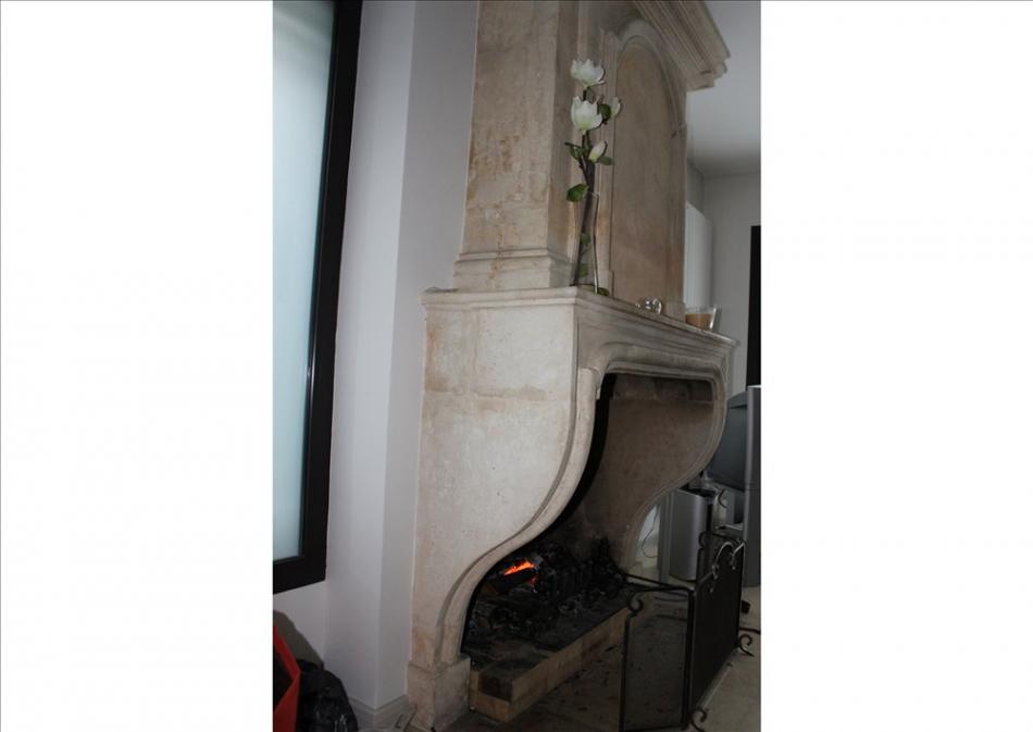 An early 18th century French Louis XIV limestone fireplace with panelled trumeau