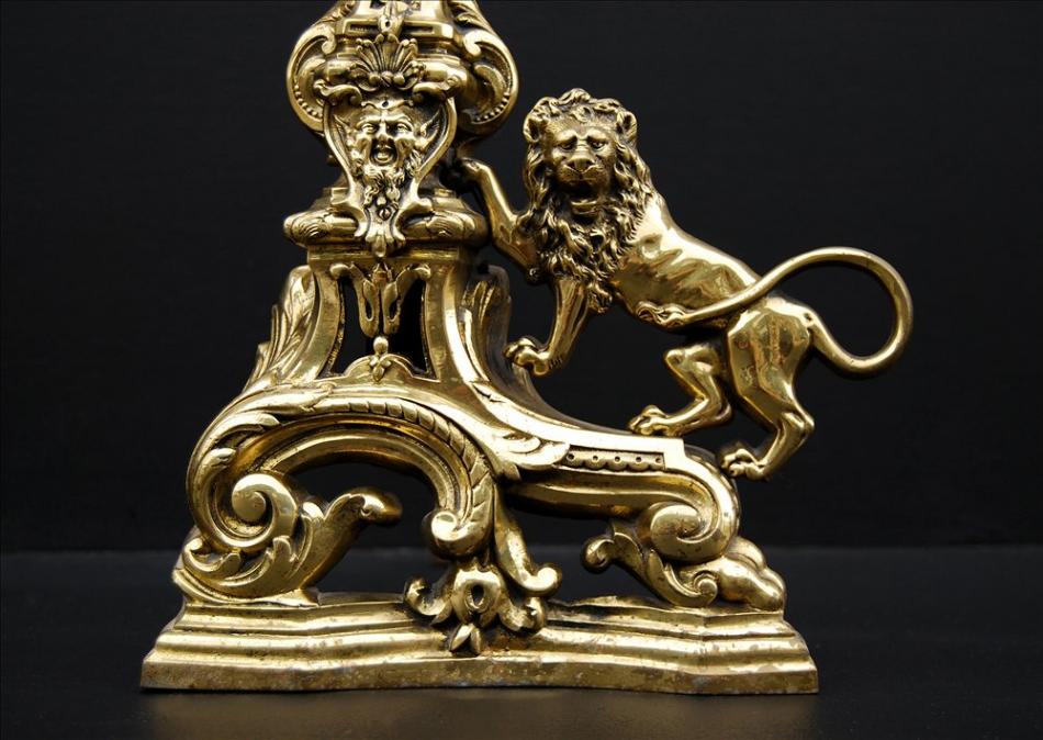 A pair of brass firedogs with lions