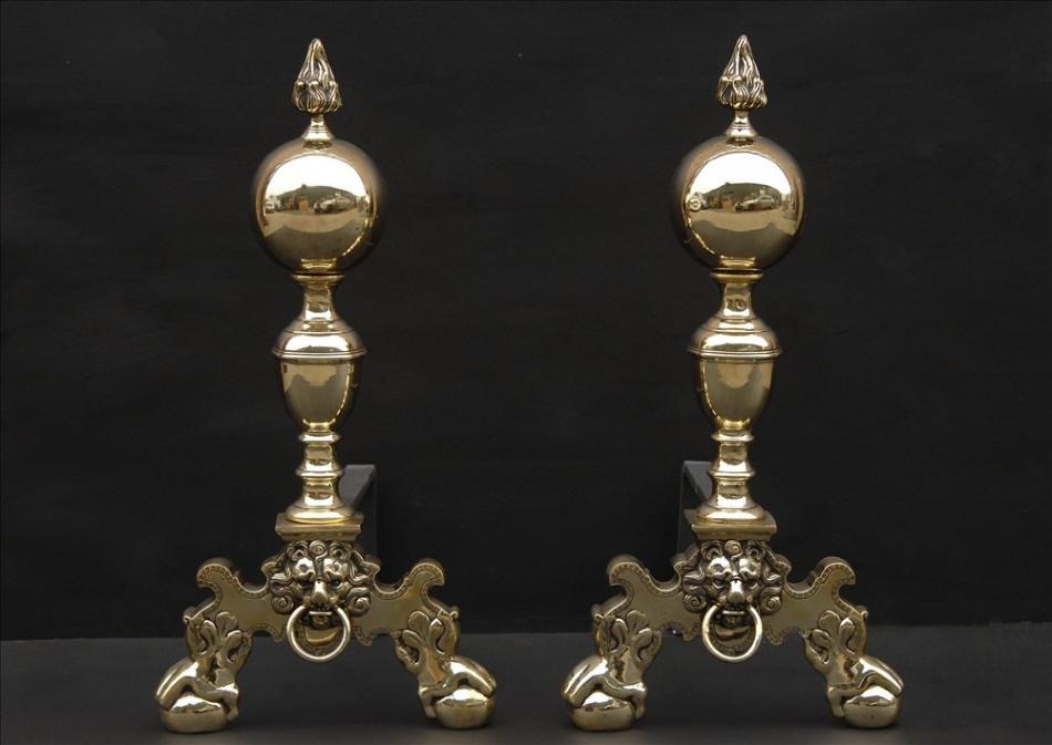 A pair of brass firedogs with flame finials