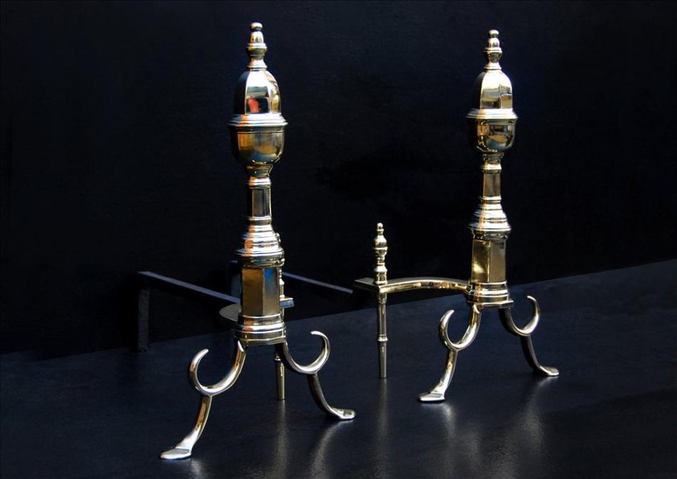 A pair of English brass firedogs with hexagonal shafts