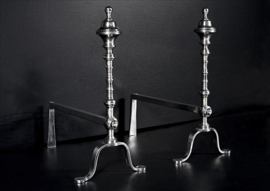 A pair of elegant polished steel firedogs