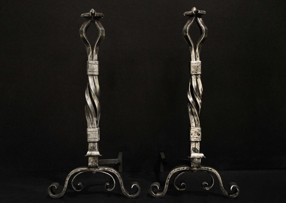 A large pair of polished wrought iron firedogs