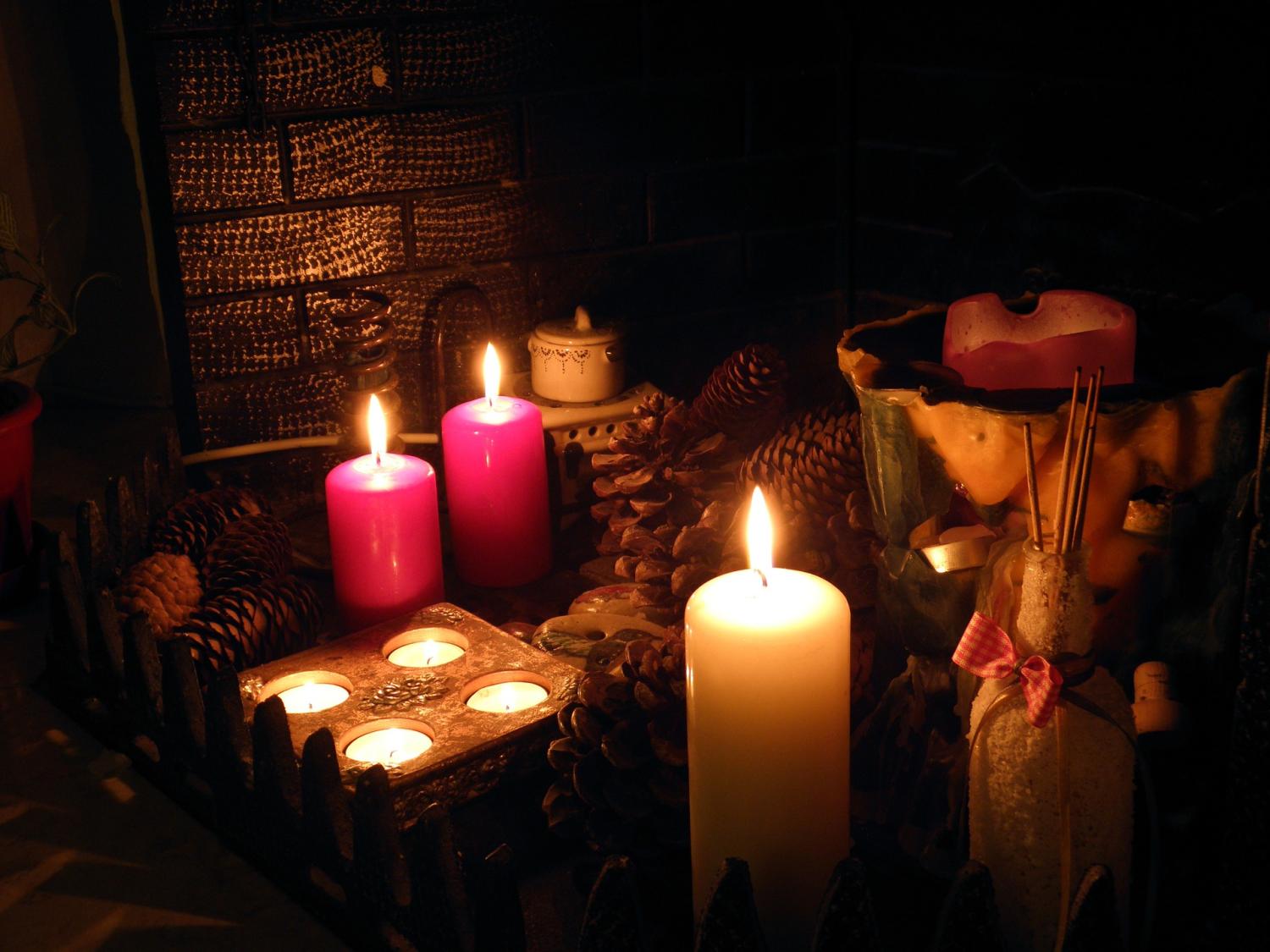 An empty fireplace has been filled with candles and pinecones