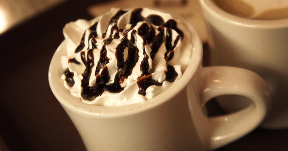 A mug of hot chocolate with cream and chocolate sauce