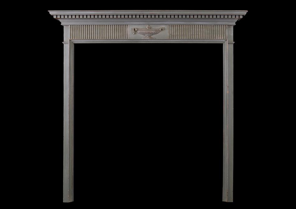 A small Regency wood fireplace with carved urn