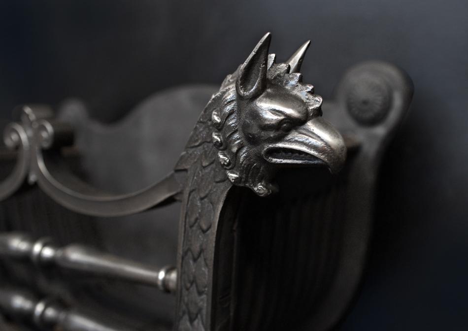A polished cast iron firegrate with griffin heads