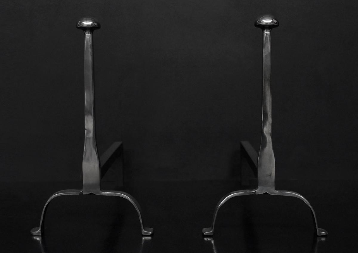 A pair of elegant firedogs in polished steel